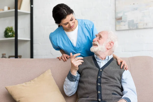 Médecin debout derrière un homme âgé, parlant à un patient heureux — Photo de stock