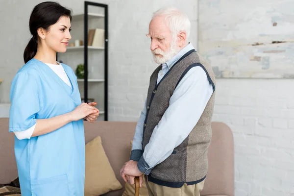 Side view of smiling nurse looking at grey haired man — Stock Photo