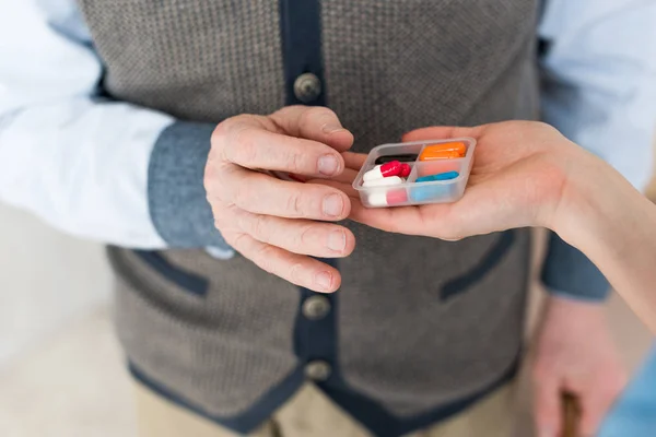 Cropped view of woman hand giving pills to elderly man — Stock Photo