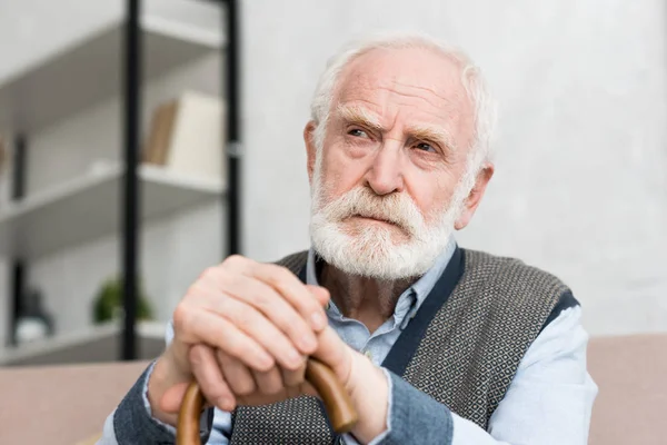 Pensive and lonely grey haired man with walking stick looking away — Stock Photo