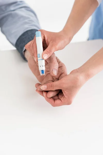 Vista ritagliata delle mani della donna che misurano la glicemia con il paziente anziano — Foto stock