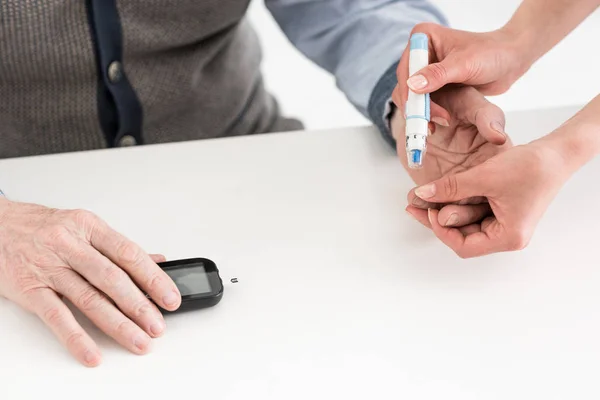 Cropped view of woman hands measuring blood sugar of senior man — Stock Photo