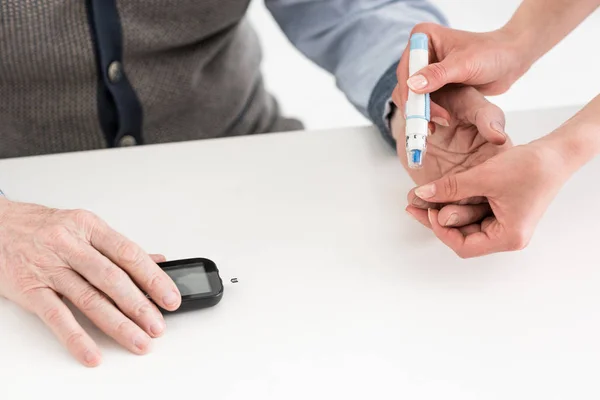 Vista recortada de las manos de la mujer que miden el azúcar en sangre del hombre mayor — Stock Photo