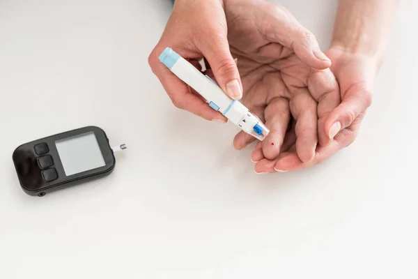 Cropped view of woman hands measuring blood sugar of senior man — Stock Photo