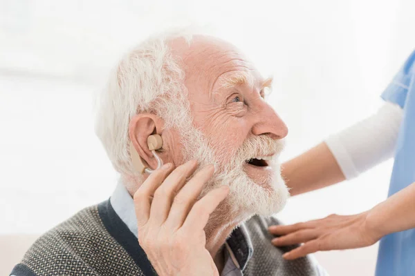 Perfil del hombre feliz y alegre con audífono en el oído, mirando hacia otro lado - foto de stock