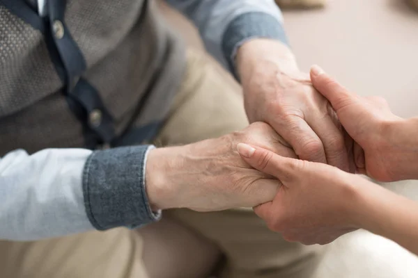 Обрізаний вид жінки, що тримає руки з літнім чоловіком — стокове фото