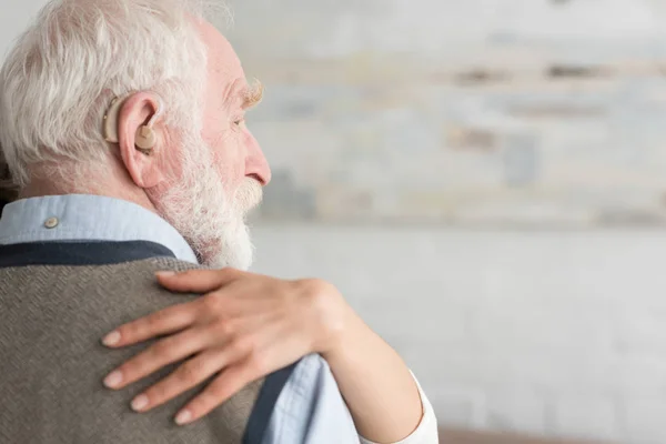 Vue recadrée de la femme mettant la main sur l'homme aux cheveux gris — Photo de stock