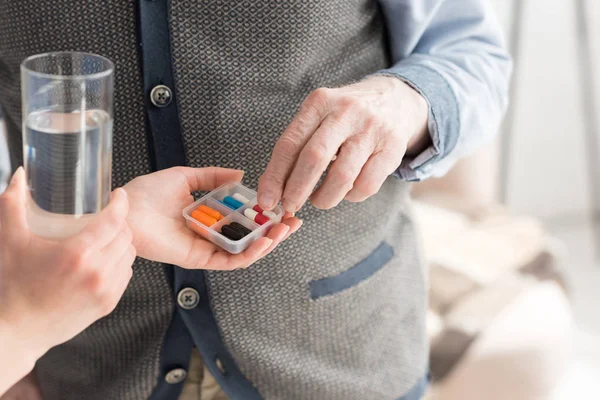 Vista recortada de la enfermera dando pastillas al hombre mayor - foto de stock