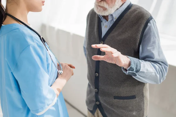 Vista recortada del gesto del hombre retirado, y hablar con la enfermera — Stock Photo