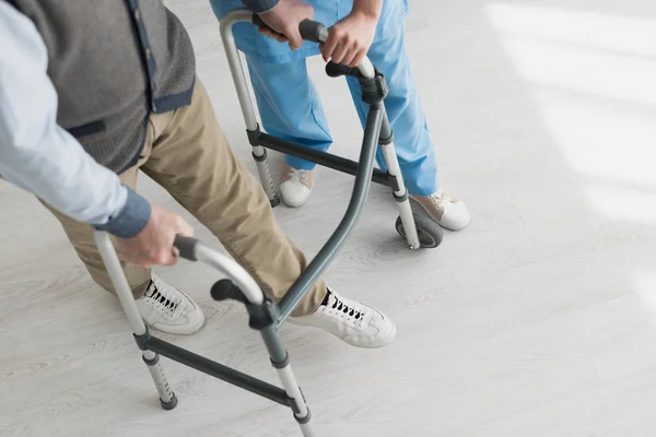 Vue en angle élevé de l'homme retraité marchant avec un médecin, se rétablissant après une blessure — Photo de stock