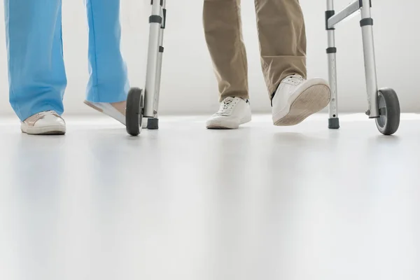 Vista cortada de médico e homem sênior andando no chão com espaço de cópia — Fotografia de Stock