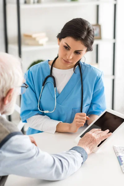 Vista recortada del hombre retirado sentado cerca del médico, y el uso de tableta digital - foto de stock