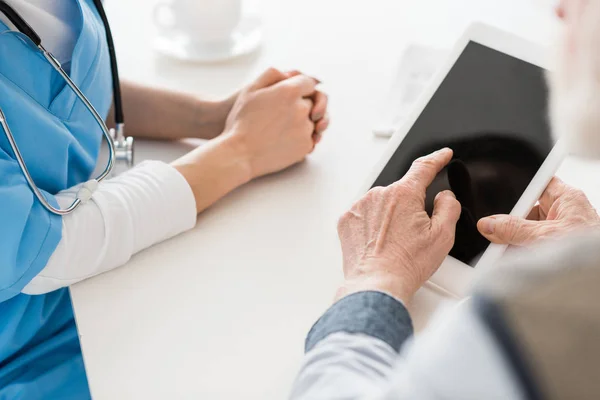 Vista recortada das mãos apontando para tablet digital com tela em branco — Fotografia de Stock