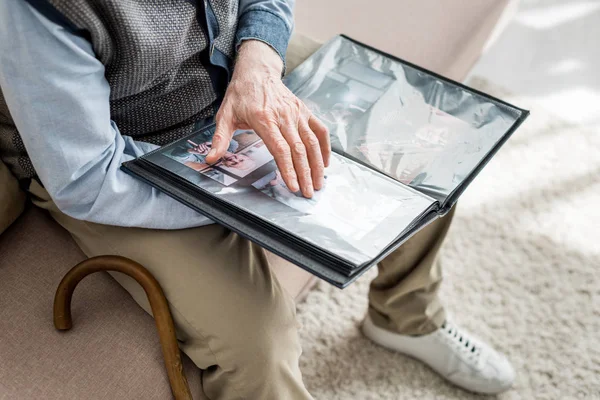 Обрізаний вид на старшого чоловіка, який тримає фотоальбом в руках — стокове фото