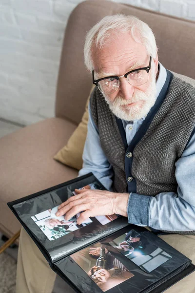 Senior man looking away, and holding photo album in hands — Stock Photo