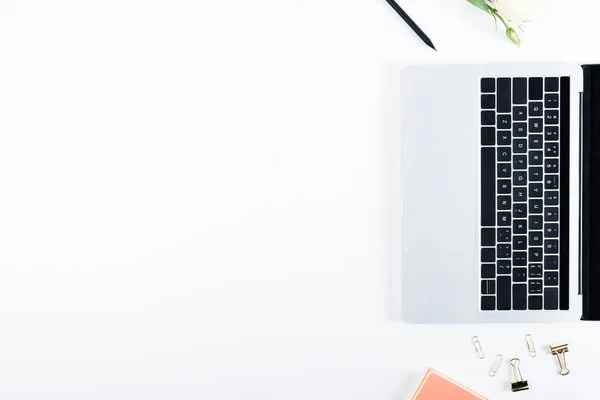 Top view of laptop, binder clips, paper clips, flower and pen on white — Stock Photo