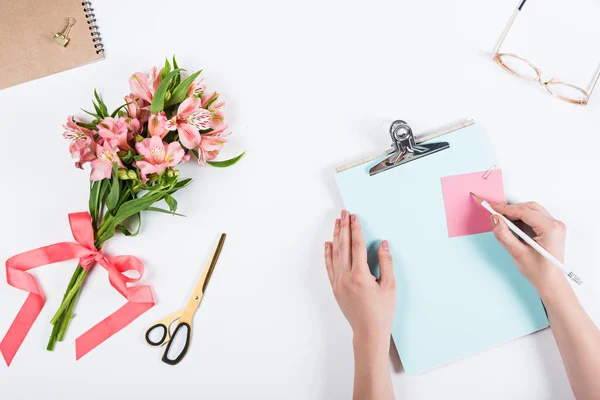 Vista ritagliata della donna che scrive su carta sul posto di lavoro — Foto stock