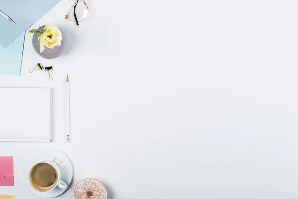 Vista superior da xícara de café, donut, livro, lápis, óculos e grampos de aglutinante em branco — Fotografia de Stock