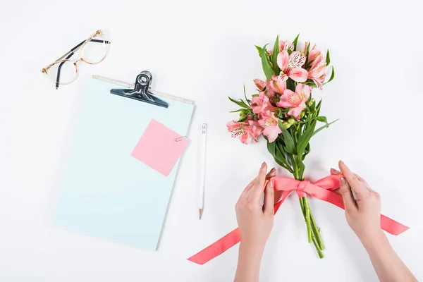 Vista recortada de la mujer atando cinta en las flores en el lugar de trabajo - foto de stock