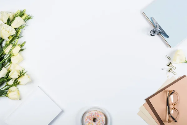 Draufsicht auf Blumen, Tasse Kaffee, Klemmbrett, Gläser, Bastelpapier und Buch auf Weiß — Stockfoto