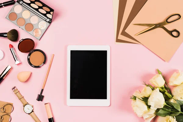 Вид сверху цифрового планшета с чистым экраном, цветами и декоративной косметикой на розовом — стоковое фото