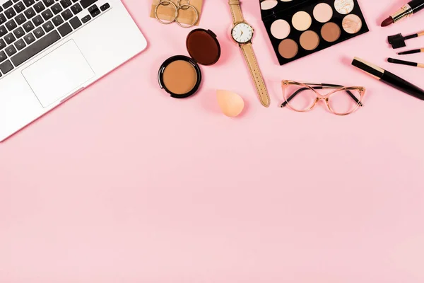 Ansicht von Laptop, Armbanduhr, Brille und dekorativer Kosmetik auf rosa — Stockfoto
