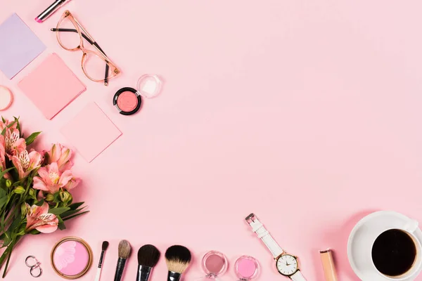 Draufsicht auf Kaffeetasse, Blumen, dekorative Kosmetik und Accessoires auf rosa — Stockfoto
