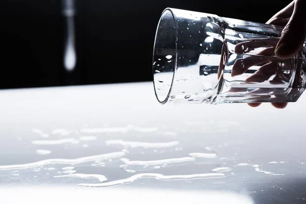 Cropped view of woman holding glass and water spots on light surface — Stock Photo