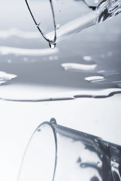 Склянка з розлитою водою і краплями на світлій поверхні — стокове фото