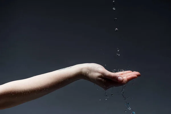 Vista recortada de la mujer con gotas de agua en la oscuridad - foto de stock