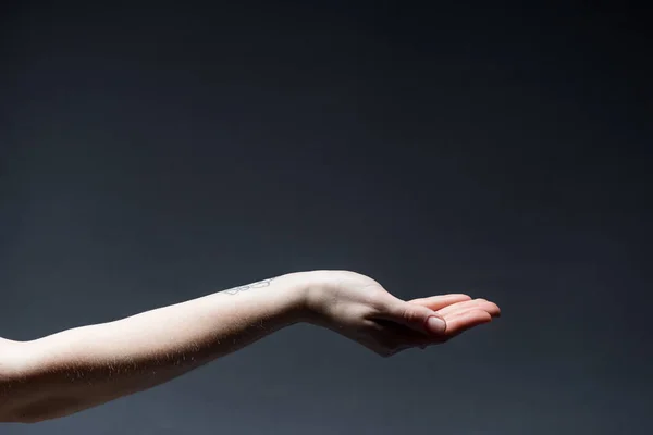 Cropped view of woman holding hand up on dark — Stock Photo
