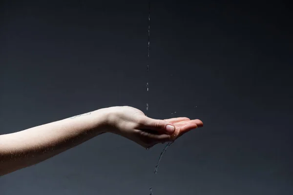 Ausgeschnittene Ansicht einer Frau mit Wassertropfen auf dunklem Grund — Stockfoto