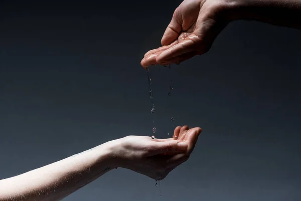 Cropped view of man and woman with water drops on dark — Stock Photo
