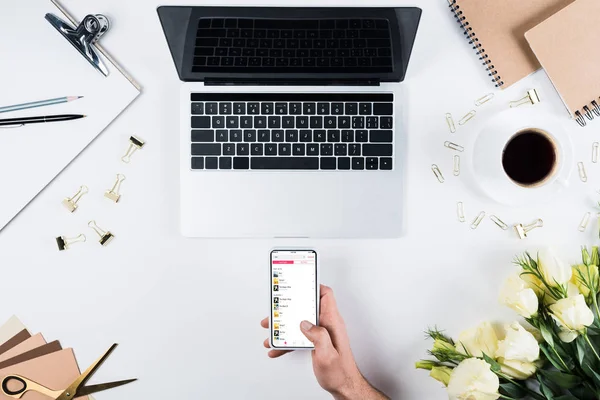 KYIV, UKRAINE - MAY 11, 2019: cropped view of man holding smartphone with apple music app on screen at workplace — Stock Photo