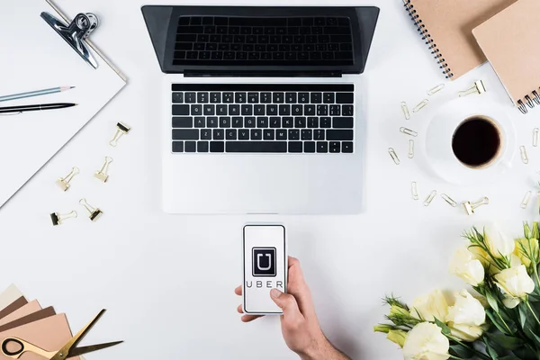 KYIV, UKRAINE - MAY 11, 2019: cropped view of man holding smartphone with uber app on screen at workplace — Stock Photo