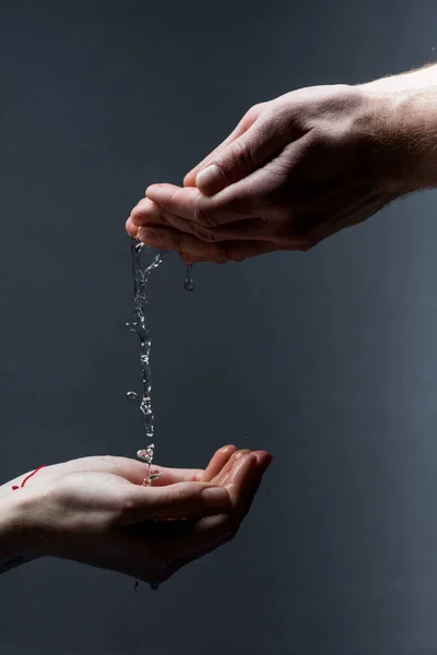 Cropped view of man and woman with water drops on dark — Stock Photo