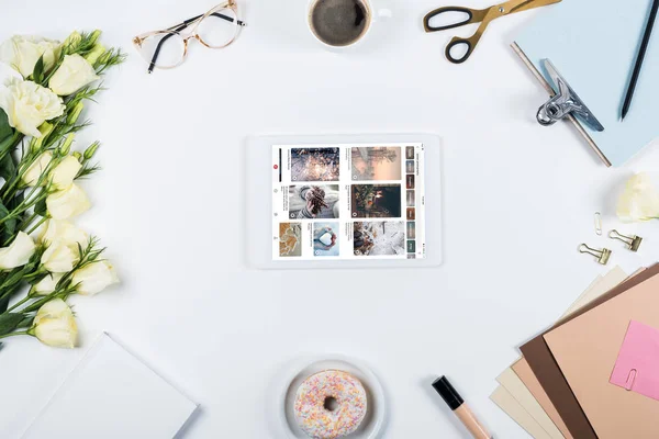 KYIV, UKRAINE - 11 MAI 2019 : vue du dessus de la tasse de café, beignet, fleurs, verres, livre, papiers, presse-papiers et tablette numérique avec l'application pinterest à l'écran sur blanc — Photo de stock