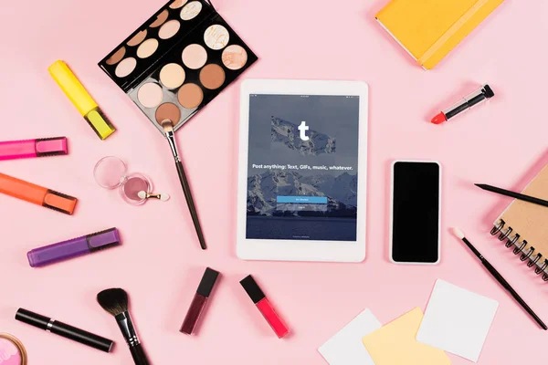 KYIV, UKRAINE - MAY 11, 2019: top view of digital tablet with tumblr app on screen, smartphone with blank screen, highlighters and decorative cosmetics on pink — Stock Photo