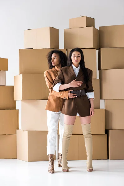 Donne afro-americane alla moda in piedi vicino a scatole su bianco — Foto stock
