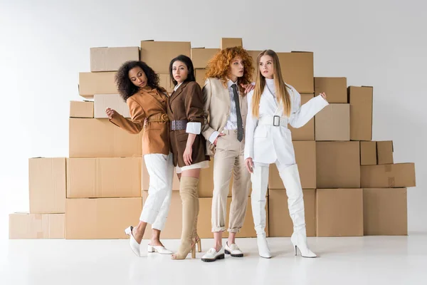 Pretty young multicultural women posing near boxes on white — Stock Photo