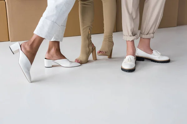 Vue recadrée de trois filles debout dans des chaussures élégantes sur blanc — Photo de stock