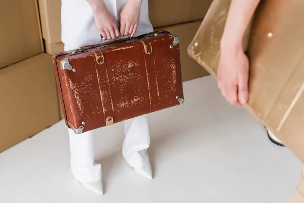 Cropped view of women holding suitcases while standing on white — Stock Photo