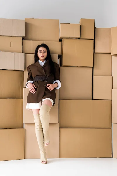 Vista de ángulo bajo de la atractiva chica afroamericana mirando a la cámara cerca de cajas en blanco - foto de stock