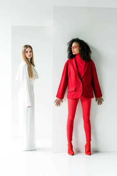 Attractive blonde girl and beautiful african american woman standing on white — Stock Photo