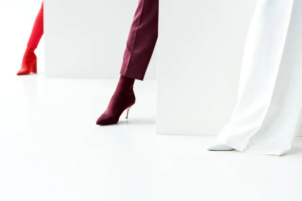 Vue recadrée de femmes élégantes debout en talons sur blanc — Photo de stock