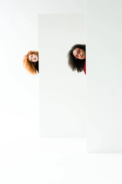 Curly redhead girl and beautiful african american woman looking at camera on white — Stock Photo