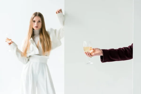 Vista recortada de la mujer sosteniendo copa de champán cerca de chica rubia en blanco — Stock Photo