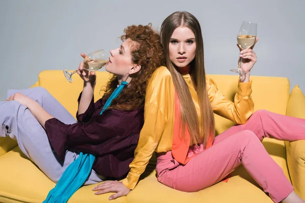 Attractive redhead girl drinking champagne near blonde young woman on white — Stock Photo