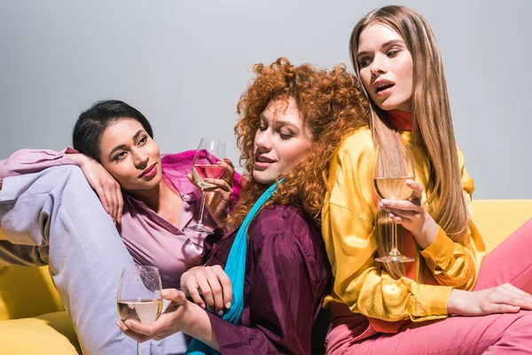 African american girl looking at redhead and blonde women with champagne glasses on white — Stock Photo