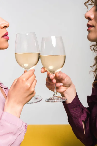 Vista recortada de las mujeres jóvenes tintineo copas de champán en blanco - foto de stock